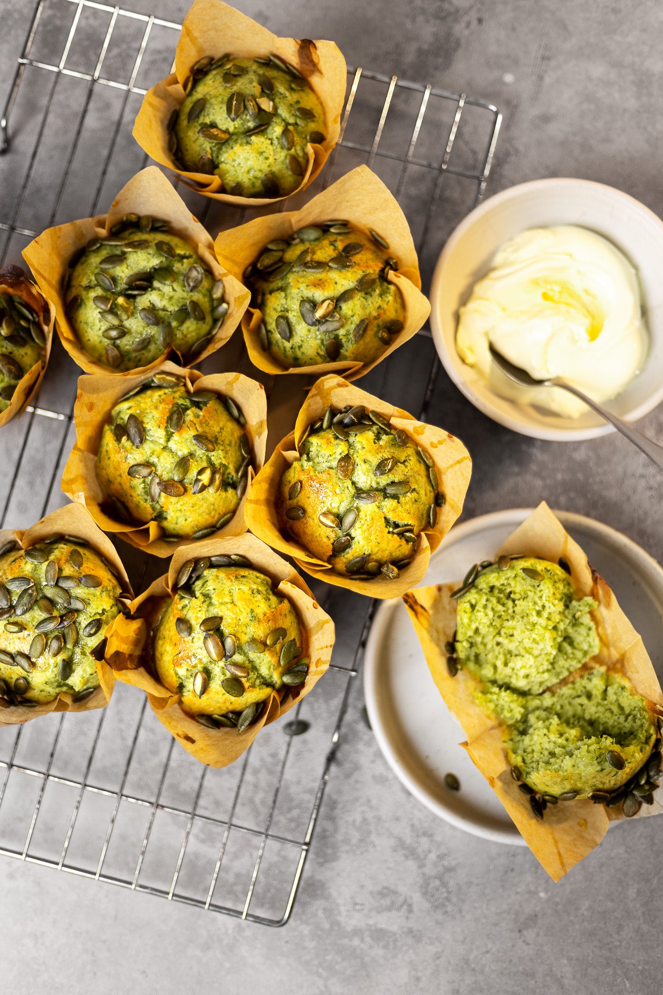 Baked muffins on a metal tray styled on a concrete-effect grey vinyl photography backdrop