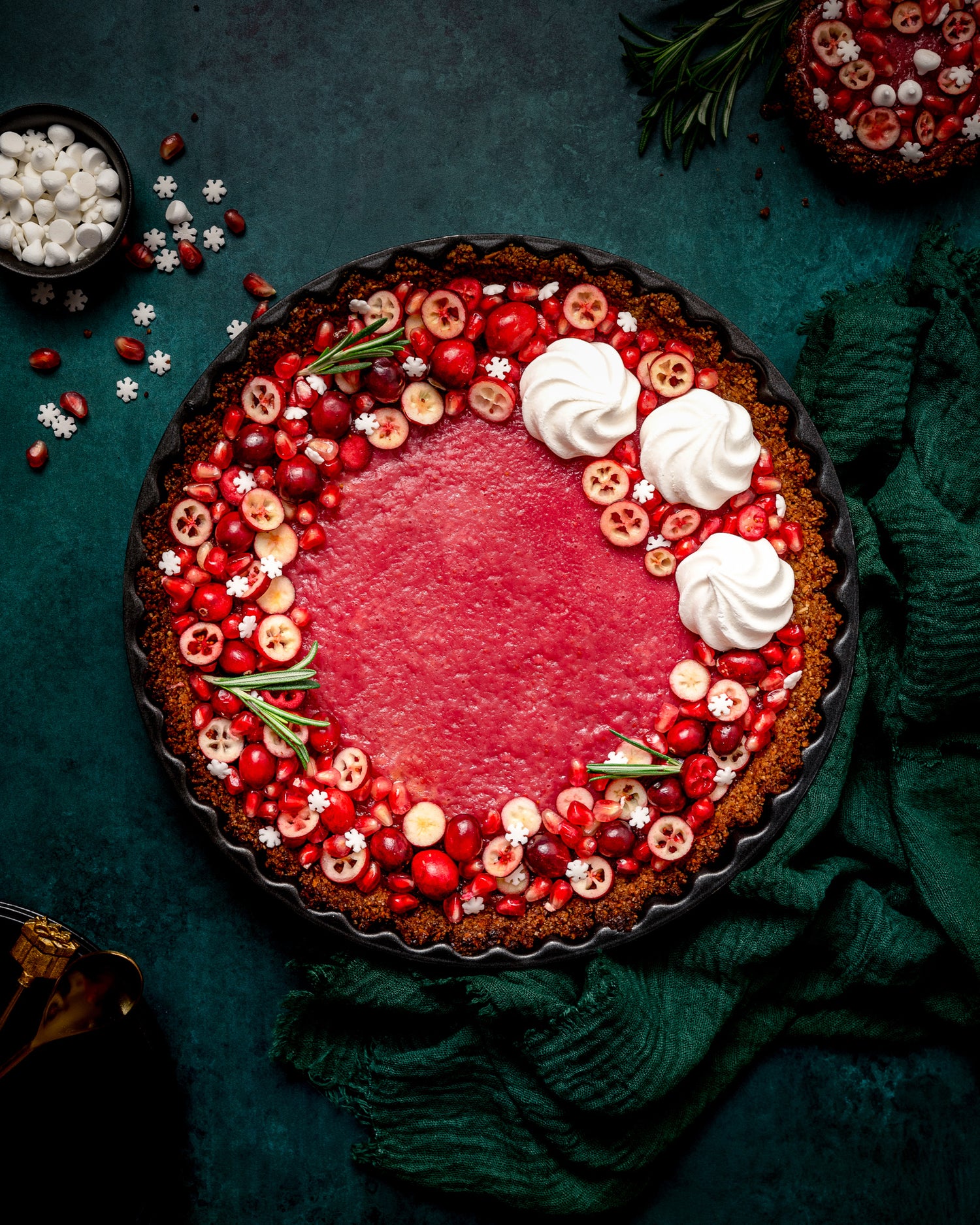 Christmas cranberry tart flat lay, styled on a dark green, textured photography backdrop with a soft mottled effect ©Anna Janecka