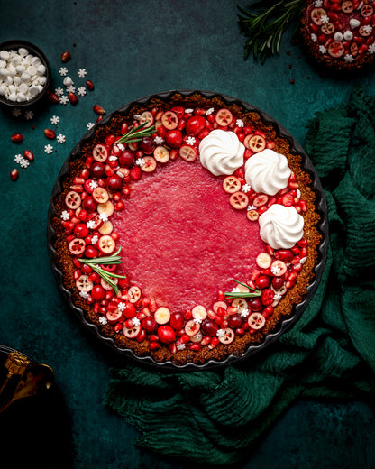 Christmas cranberry tart flat lay, styled on a dark green, textured photography backdrop with a soft mottled effect ©Anna Janecka
