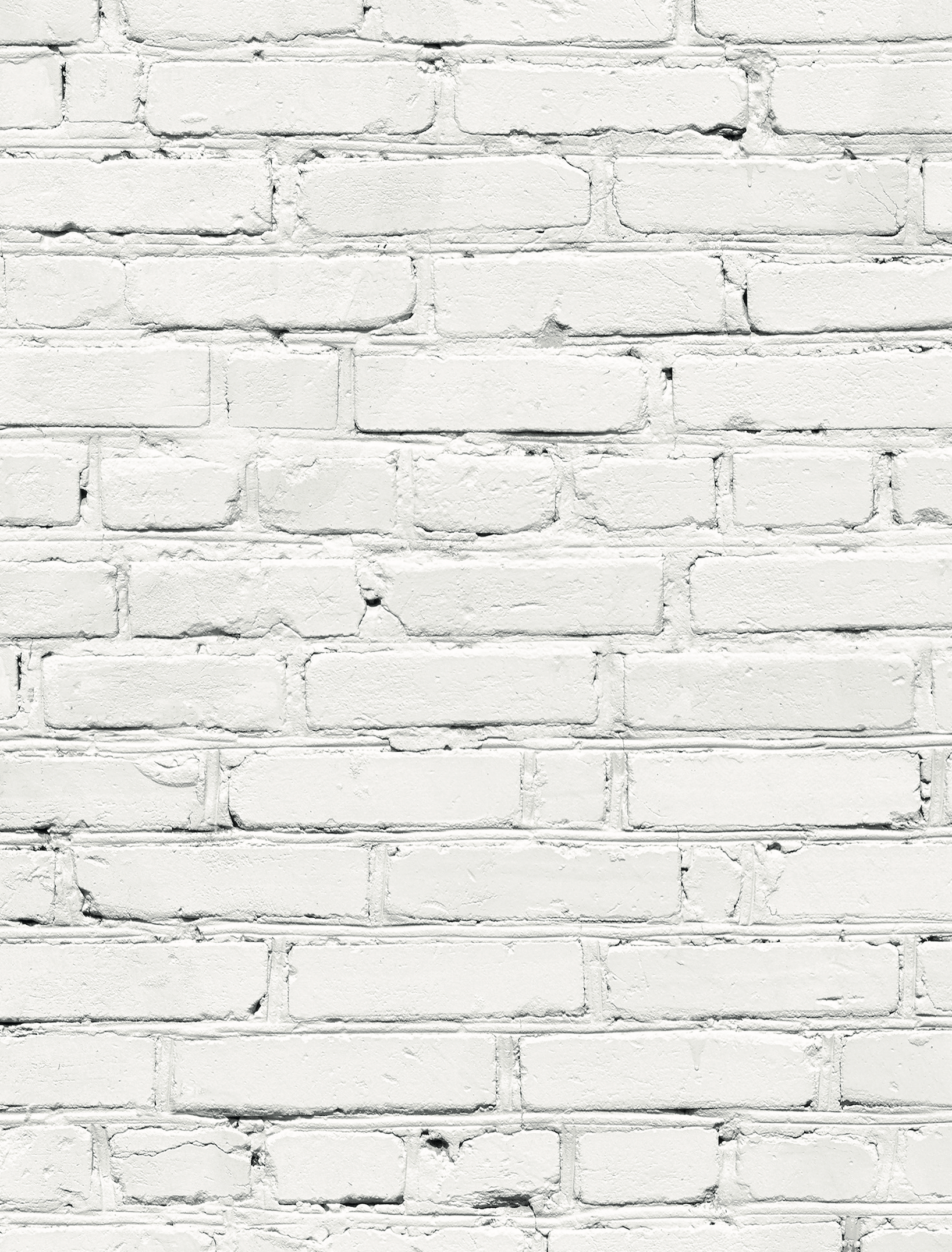 A close up of a white brick wall-effect vinyl photography backdrop with varying shades of grey and mortar lines designed to mimic a brick wall texture.