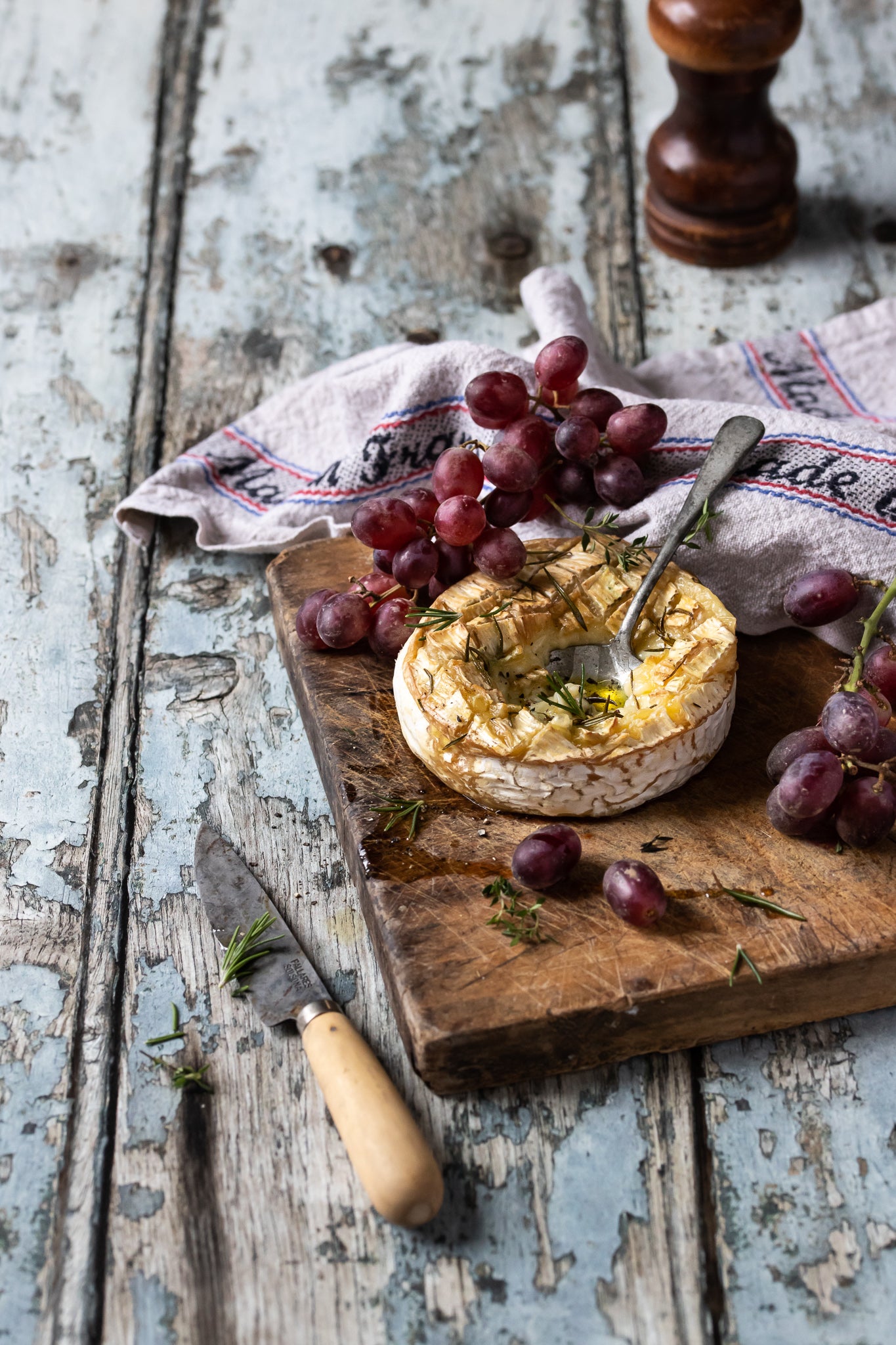 Old vintage flakey wood effect photography backdrop with a wooden board of Camembert cheese and grapes.