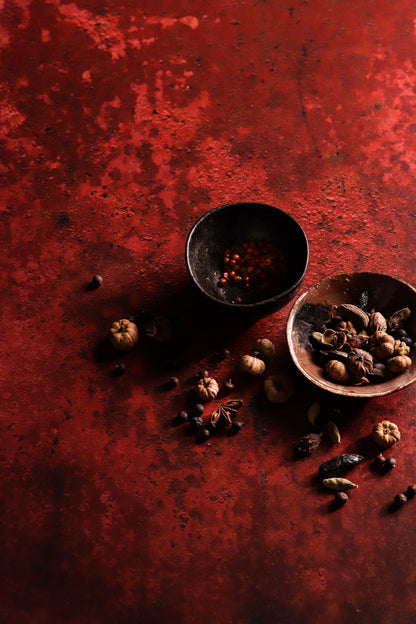 Flat lay shot of two small rustic bowls of nuts styled on a highly textured rusty red metal effect photography backdrop used for food and product styling.