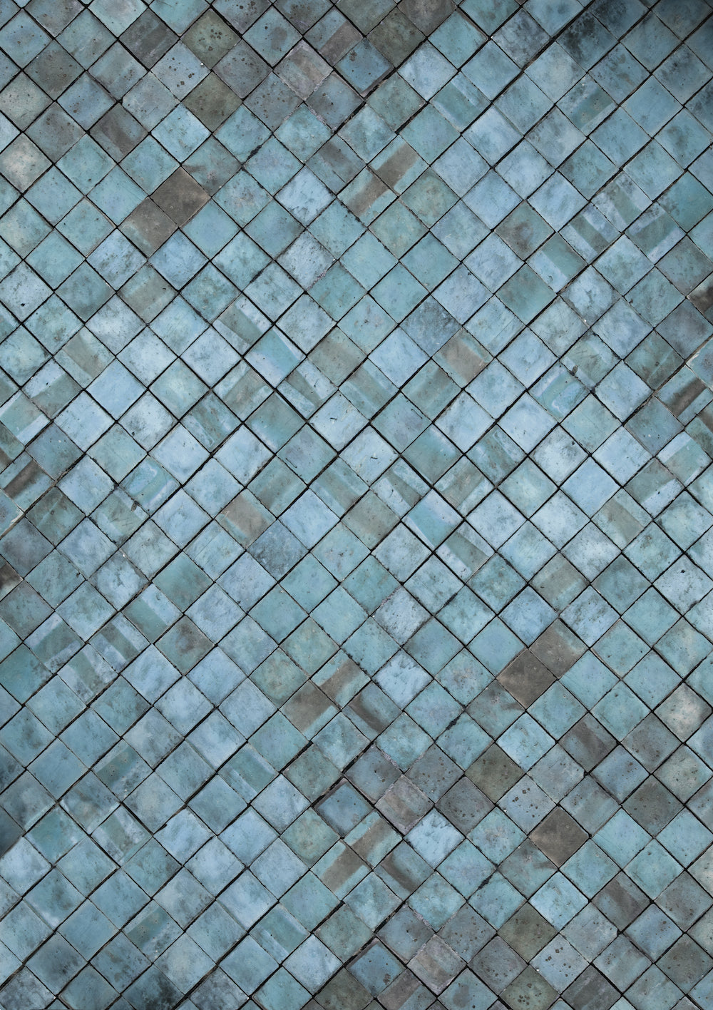 A close-up image of a blue tile effect photography backdrop with a weathered patina in greys and taupe.