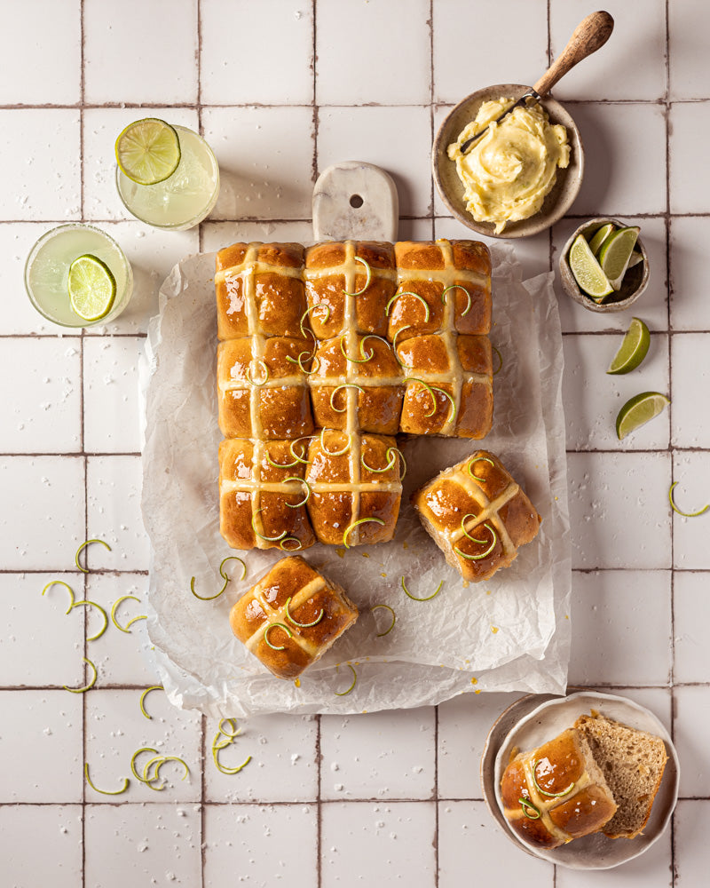 Flat lay of Margarita Hot Cross Buns styled on a white tile effect photography backdrop with a subtle gray grid lines texture.