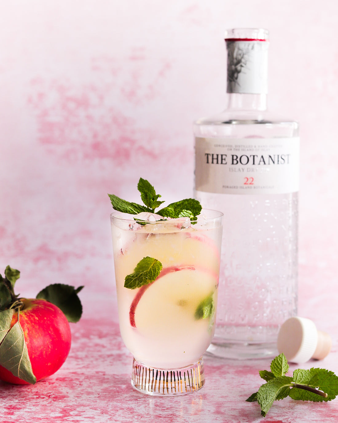 Gin and apple drink on pink plaster backdrop