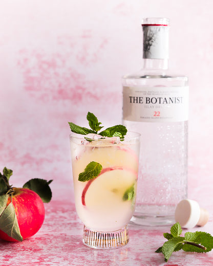 Gin and apple drink on pink plaster backdrop