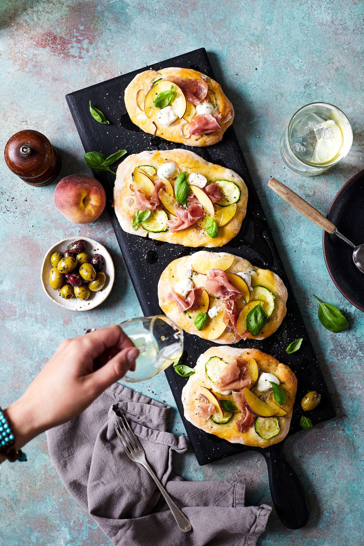A food styling image of mini summer styled pizzas on a green mottled vinyl photography backdrop