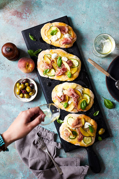 A food styling image of mini summer styled pizzas on a green mottled vinyl photography backdrop