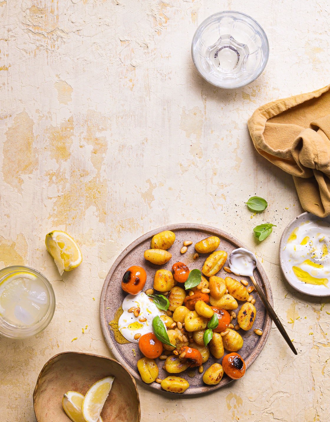 A colourful food photo of a plate of gnocchi styled on a crackled yellow paint effect photography backdrop for food and product styling.