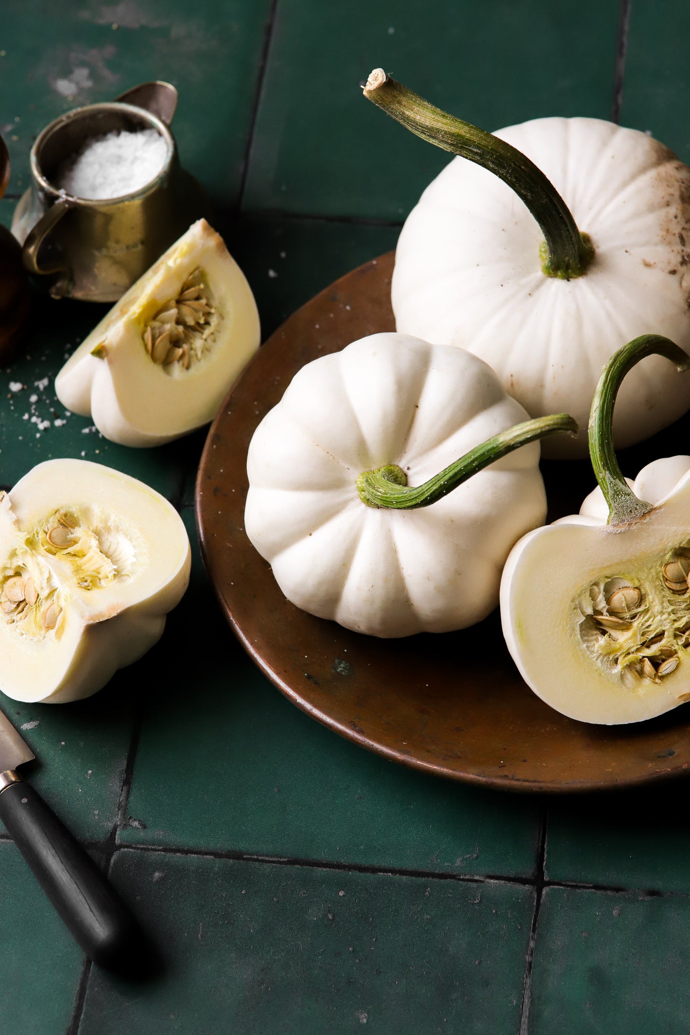 A styled image of white squash on a green tile effect photography backdrop with an irregular patina.
